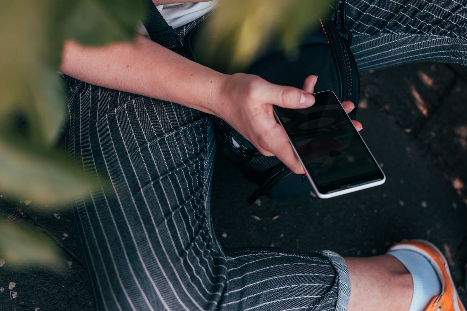 A person sitting outdoors holding a smartphone